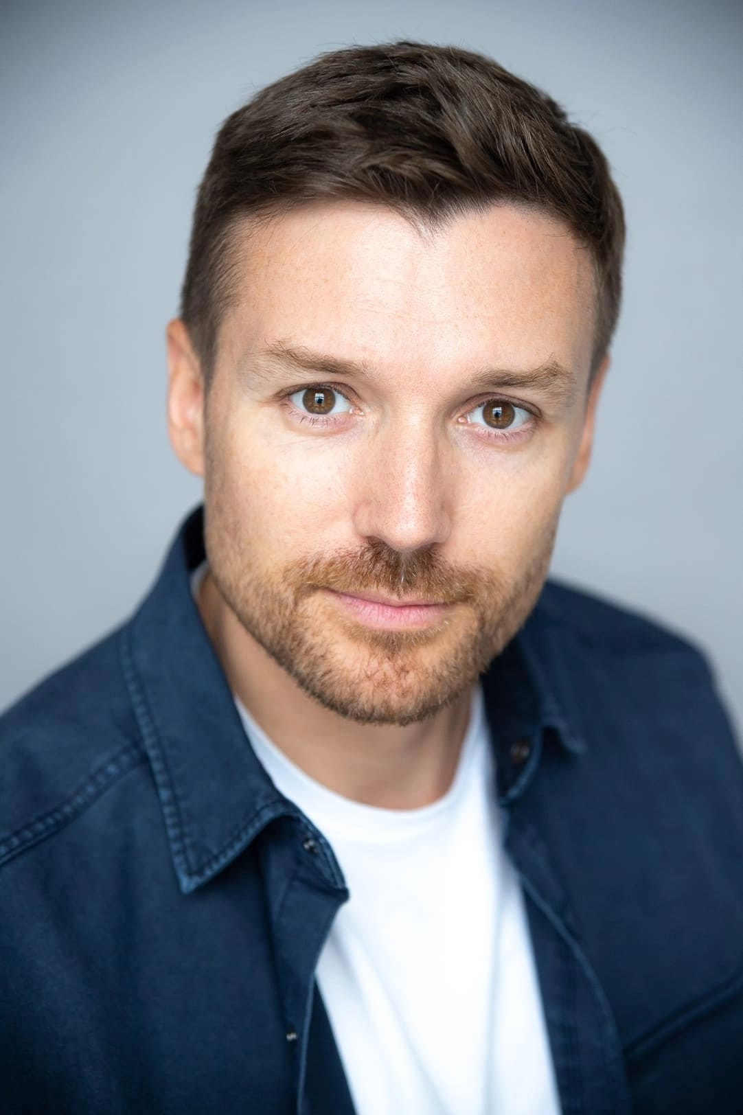 Портрет кареглазого мужчины с короткой щетиной в синей рубашке