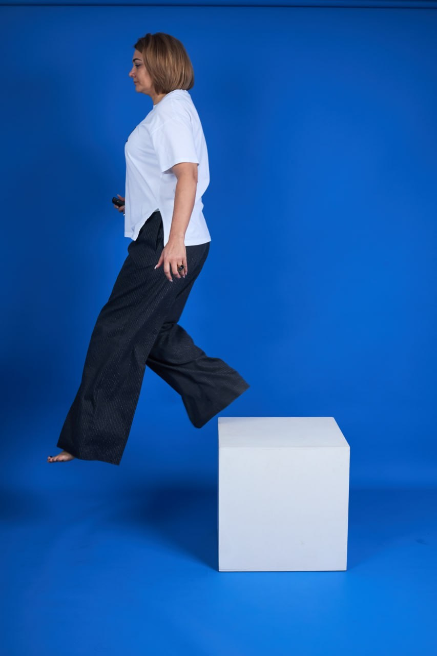 Девушка шагает с белого куба на голубом фоне