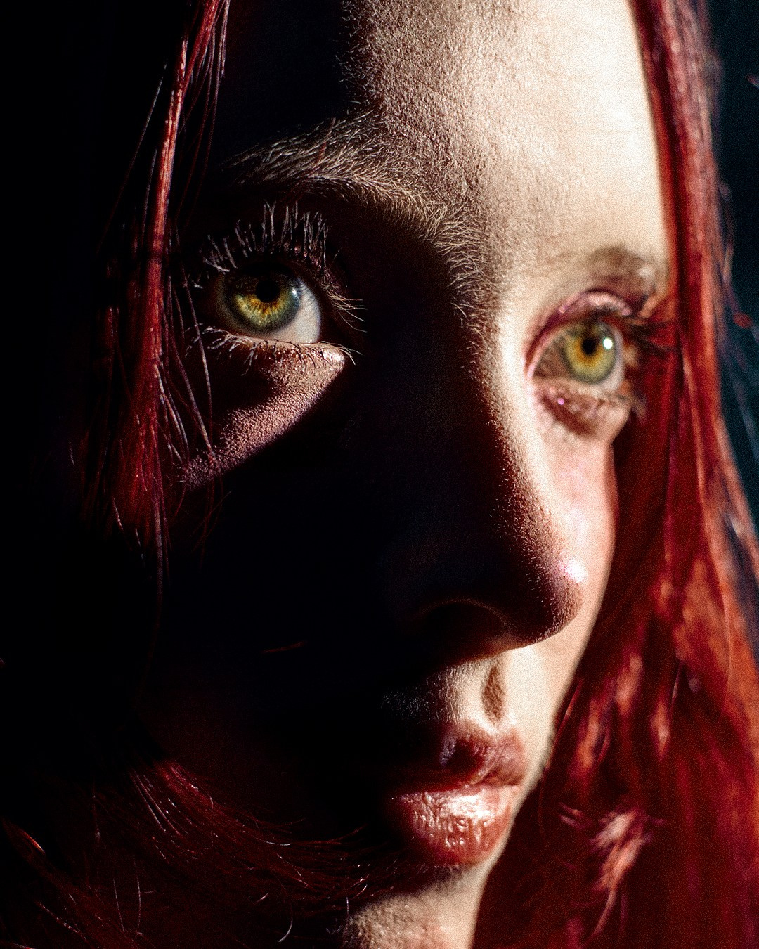 Крупный кадр молодой рыжей девушки в студии, рыжеволосая девушка смотрит сосредоточенно