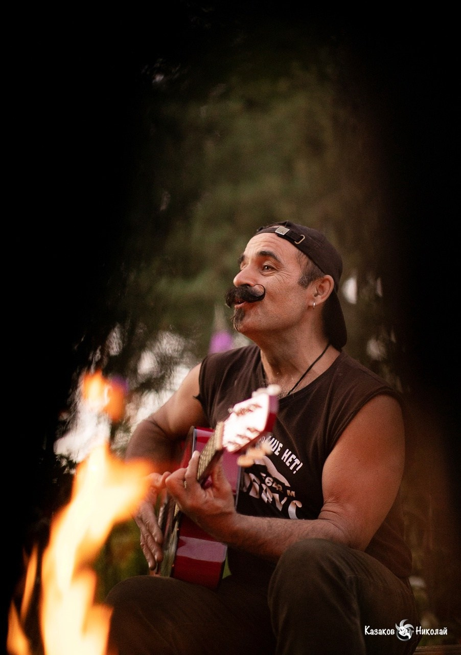 Михаил Новицкий исполняет песню у костра во время концерта на даче