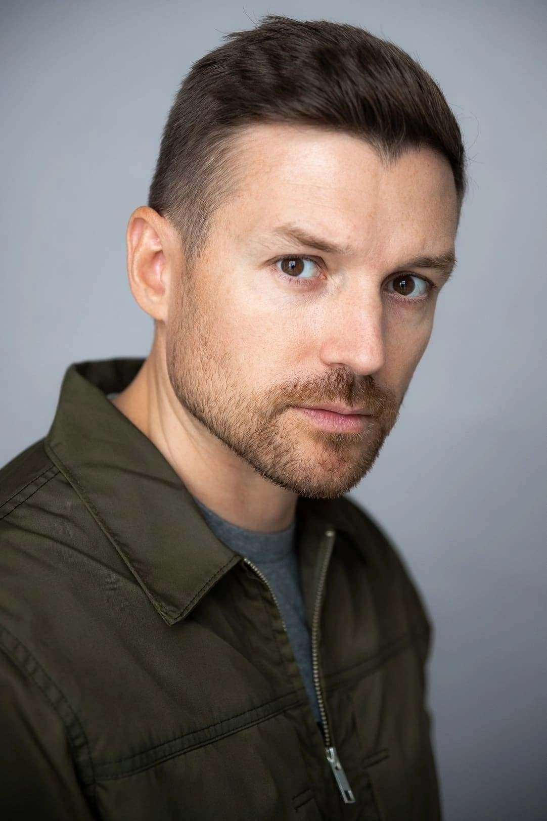 Портрет мужчины с короткой щетиной в зеленой куртке