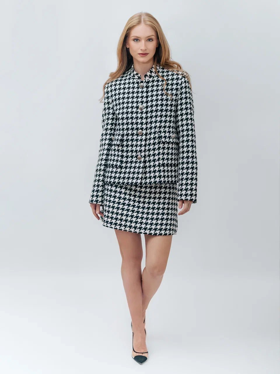 Девушка в черно-белом пиджаке и короткой юбке на сером фоне