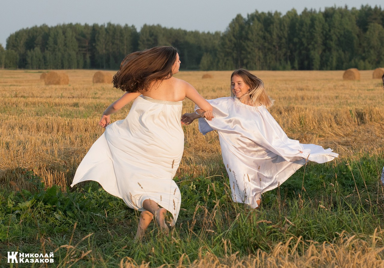 Стройные девочки подростки танцуют в пшеничном поле во время фотосессии на закате.
