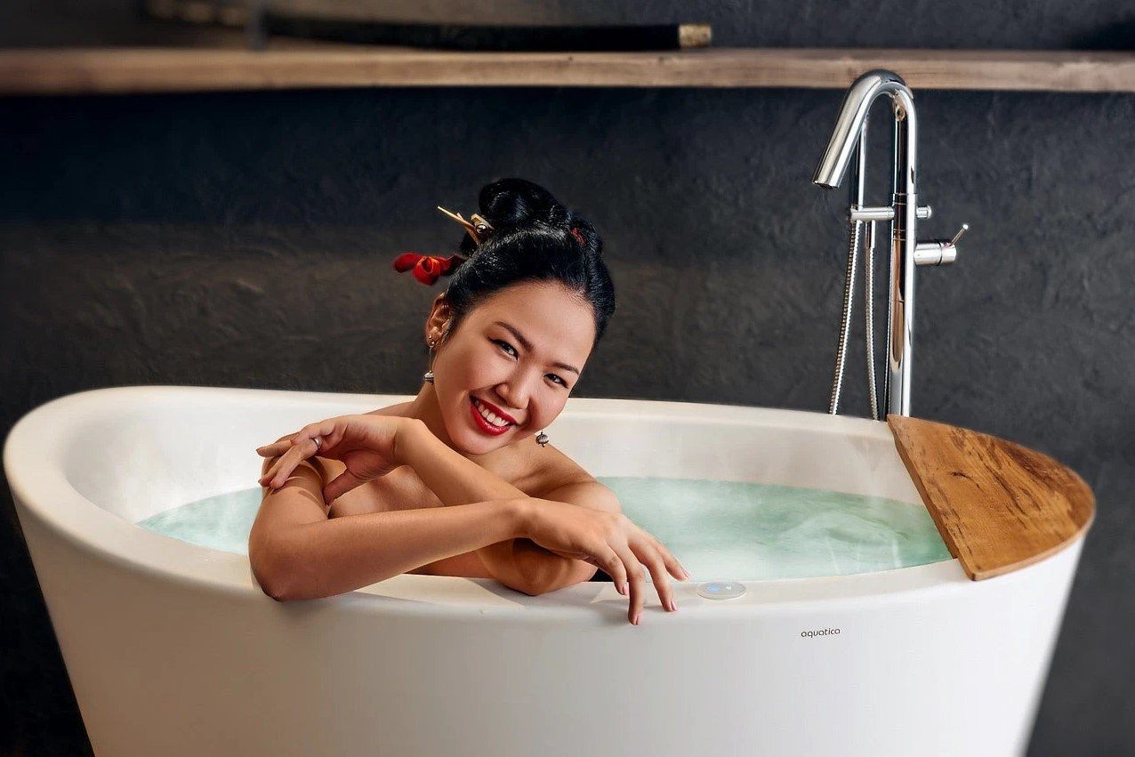 профессиональная интерьерная съёмка женщины в отдельностоящей ванне с деревянным столиком