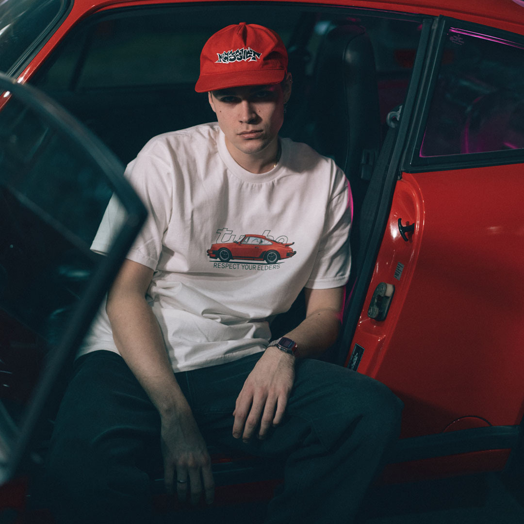 Молодой парень в мужской футболке с логотипом Porsche 911