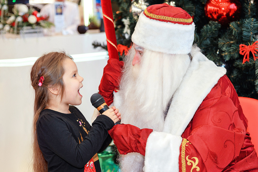 Девочка возле ёлки читает стих Деду Морозу.