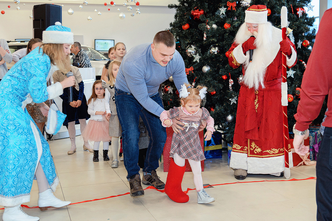 Папа с дочкой участвуют в конкурсе от Деда Мороза возле новогодней ёлки.