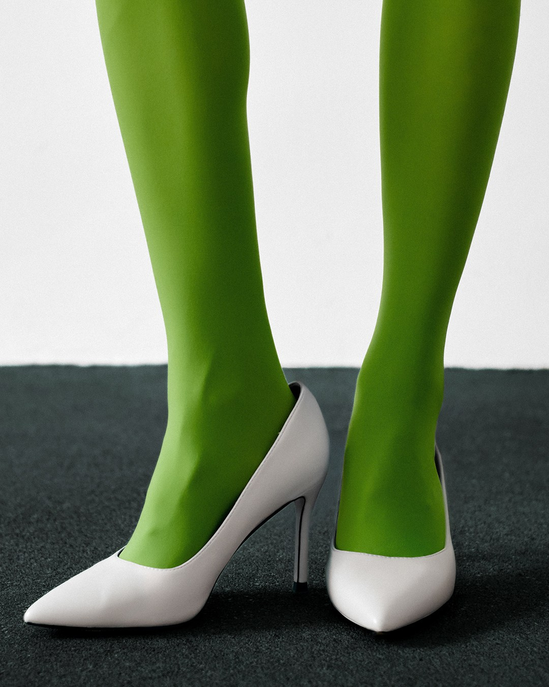 Женские ноги в зеленых колготках и белых туфлях