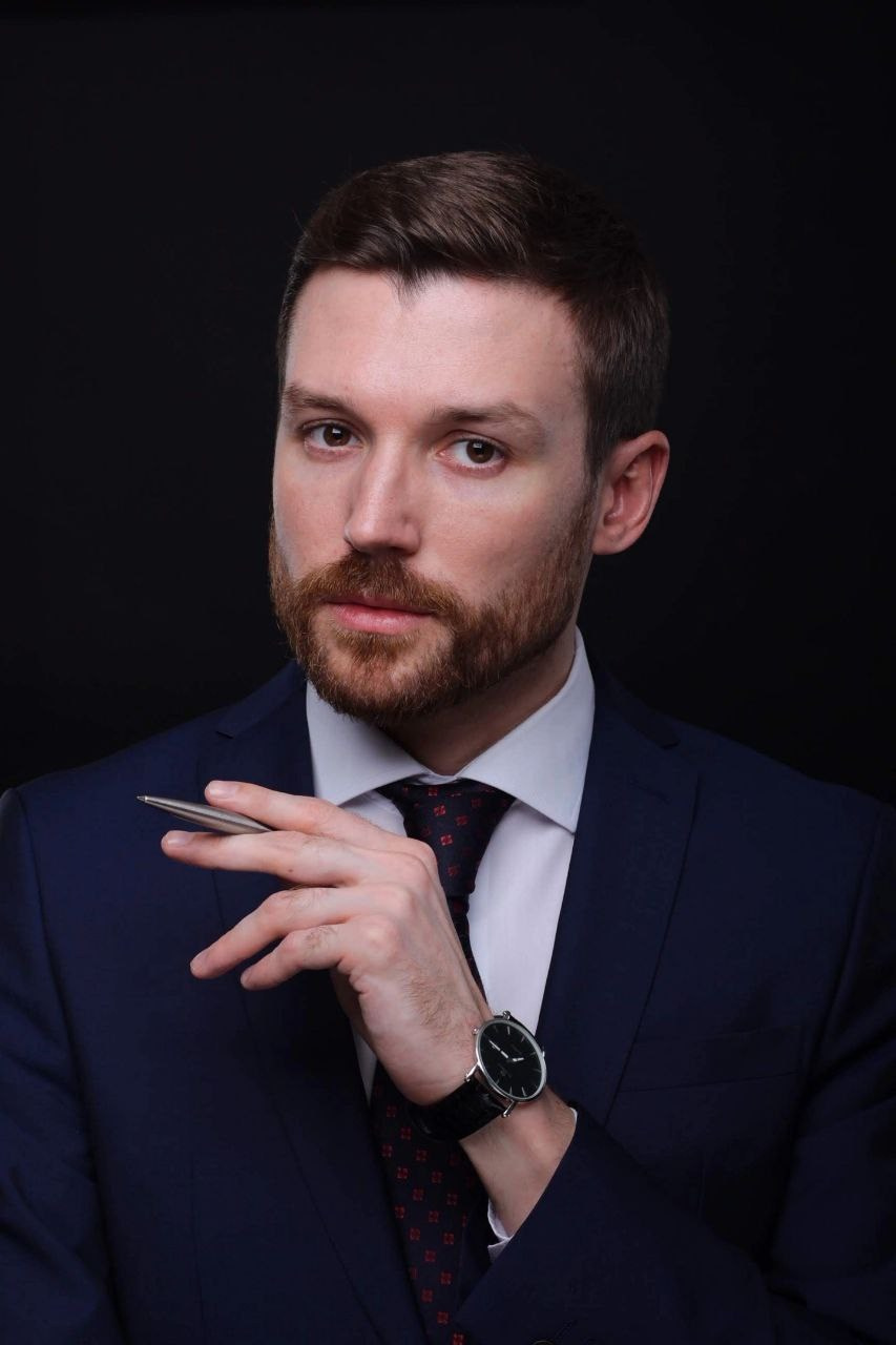 Портрет мужчины с короткой бородой, в пиджаке, галстуке и пишущей ручкой в руке