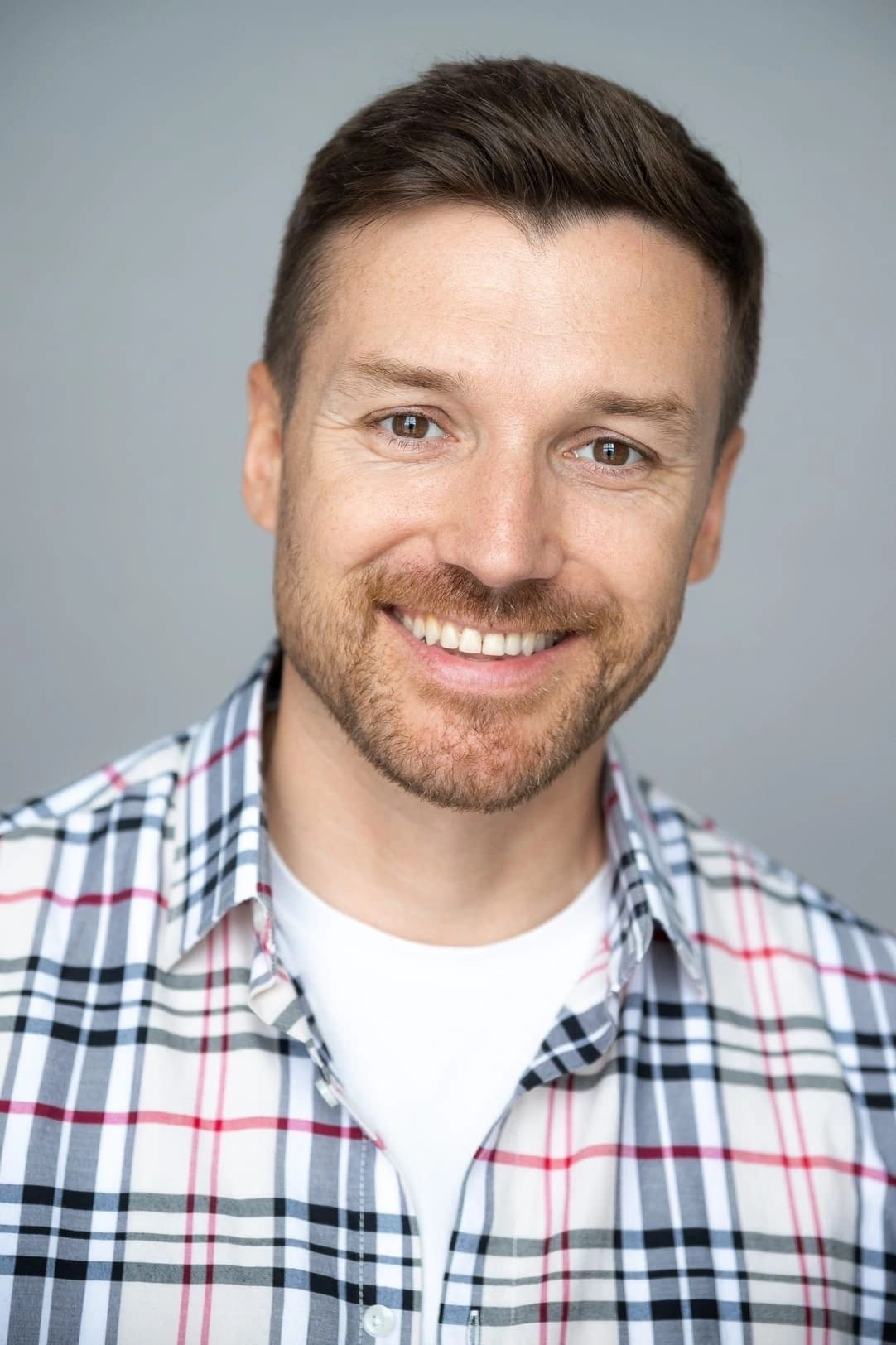 Портрет кареглазого мужчины с короткой щетиной в клетчатой рубашке