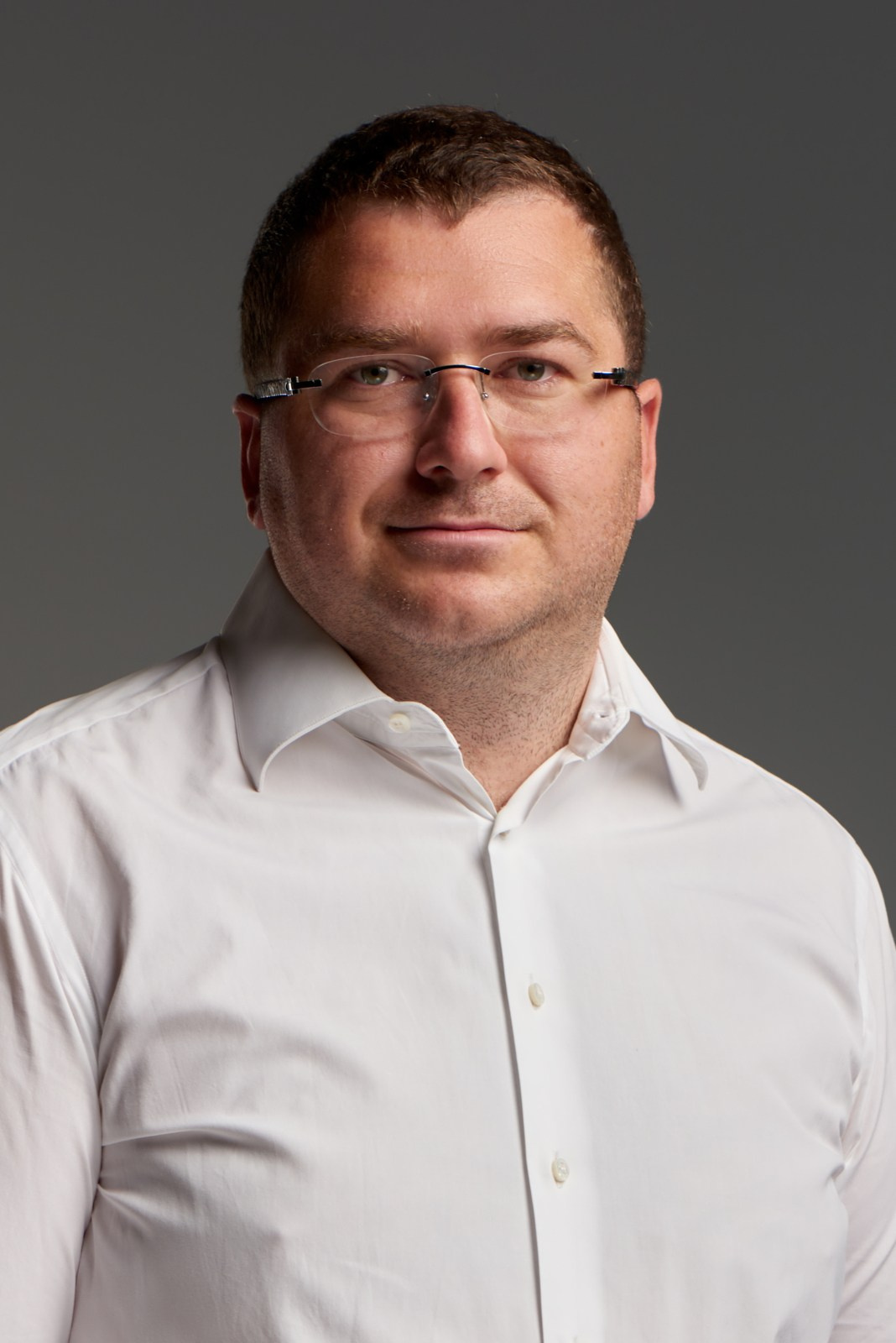 Бизнес-портрет мужчины в очках на тёмном фоне — серьёзность, профессиональность, надёжность.