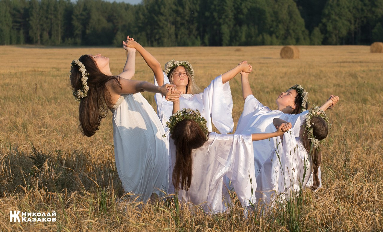 Стройные девочки подростки танцуют в пшеничном поле во время фотосессии на закате.
