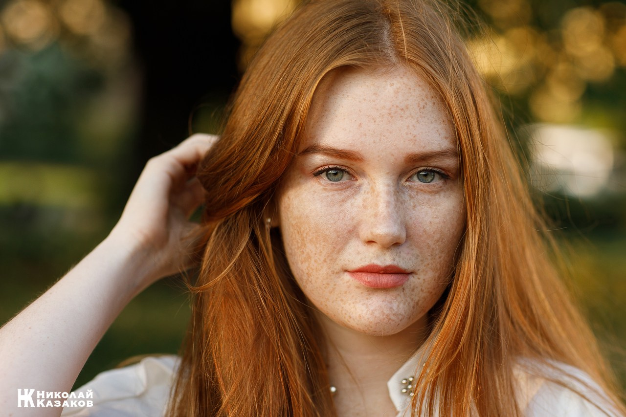Стильная молодая рыжеволосая девушка в лучах закатного летнего солнца в Питере.