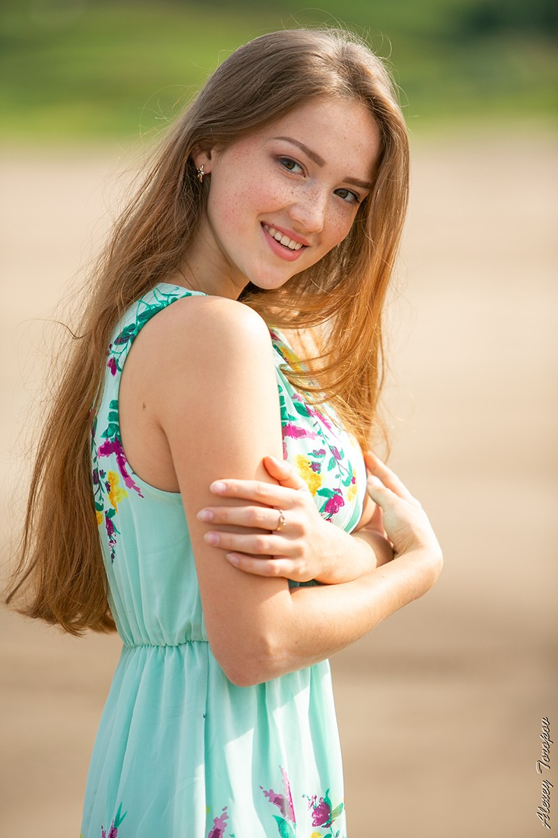 Молодая девушка позирует на фоне песка