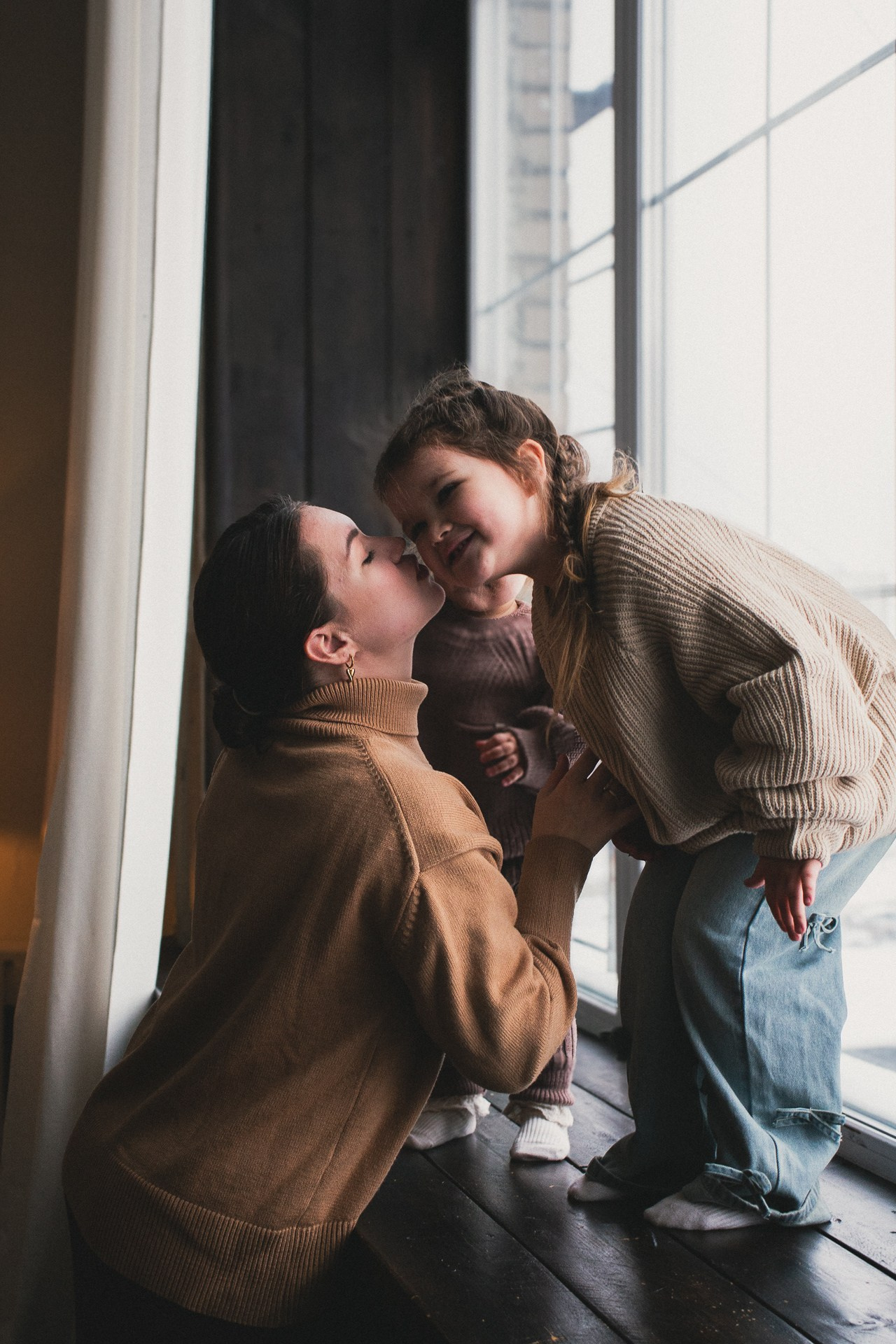Студийная семейная фотосессия - мама с двумя детьми у окна в естественном свете