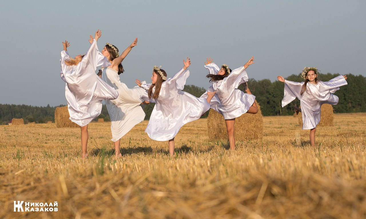Стройные девочки подростки танцуют в пшеничном поле во время фотосессии на закате.