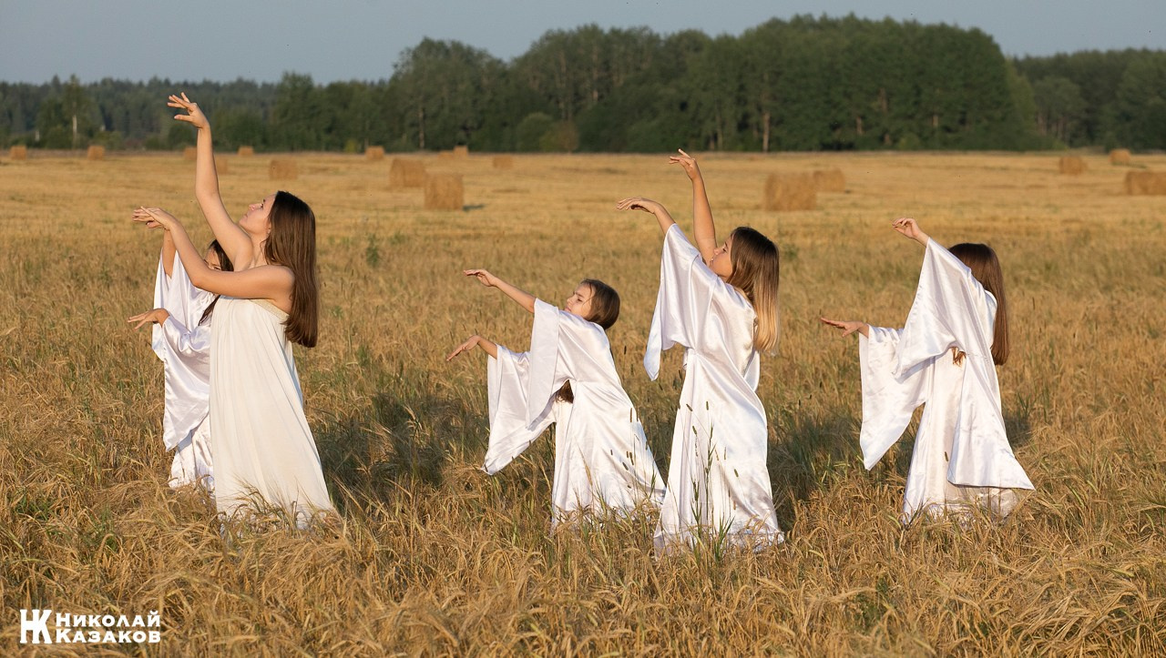Стройные девочки подростки танцуют в пшеничном поле во время фотосессии на закате.