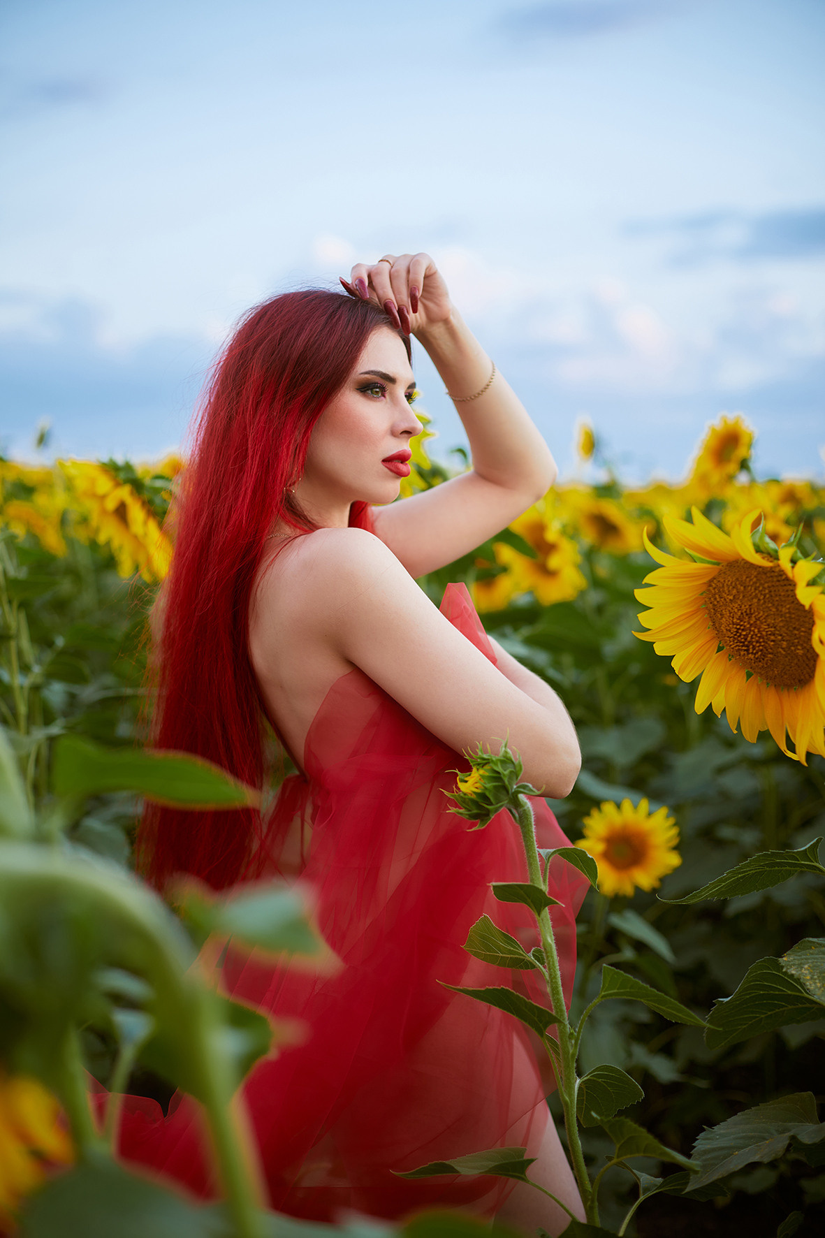 Портрет красивой девушки с красными волосами в красной ткани в поле с цветущими подсолнухами. Фотограф. Тимашевск. Кубань. Краснодарский край.