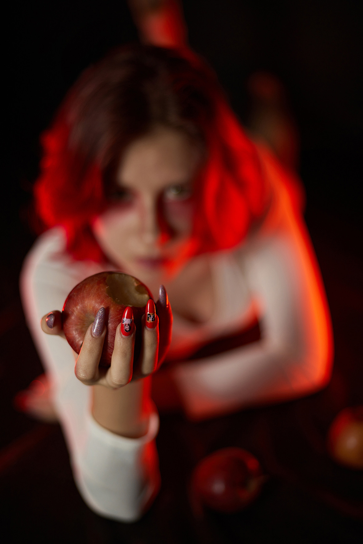 Девушка с красными волосами в белом боди лежит на черном фоне с красными яблоками. Красный макияж. Фотограф. Краснодарский край. Тимашевск. Кубань.