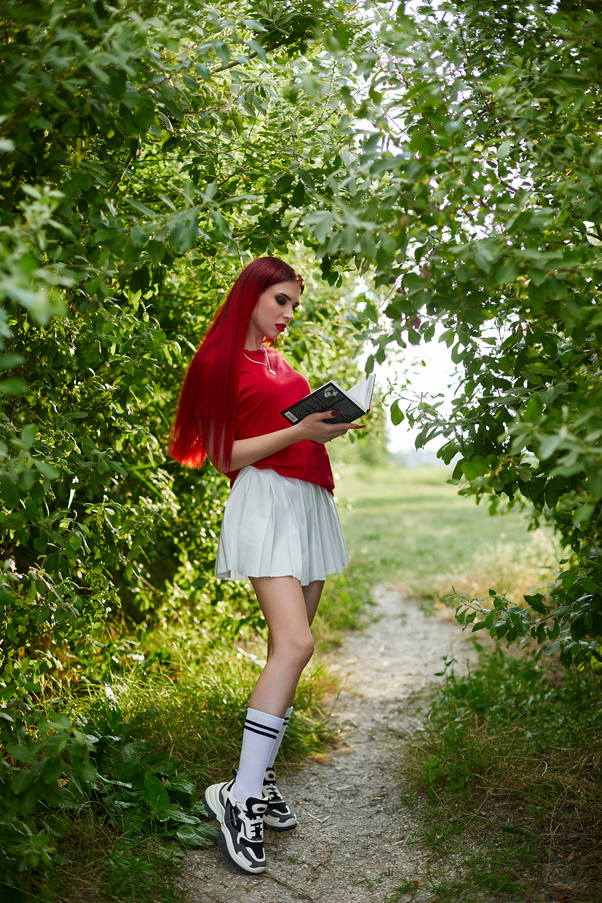 Девушка с красными волосами читает книгу Стивена Кинга в саду среди деревьев. Фотограф. Тимашевск. Кубань. Краснодарский край.
