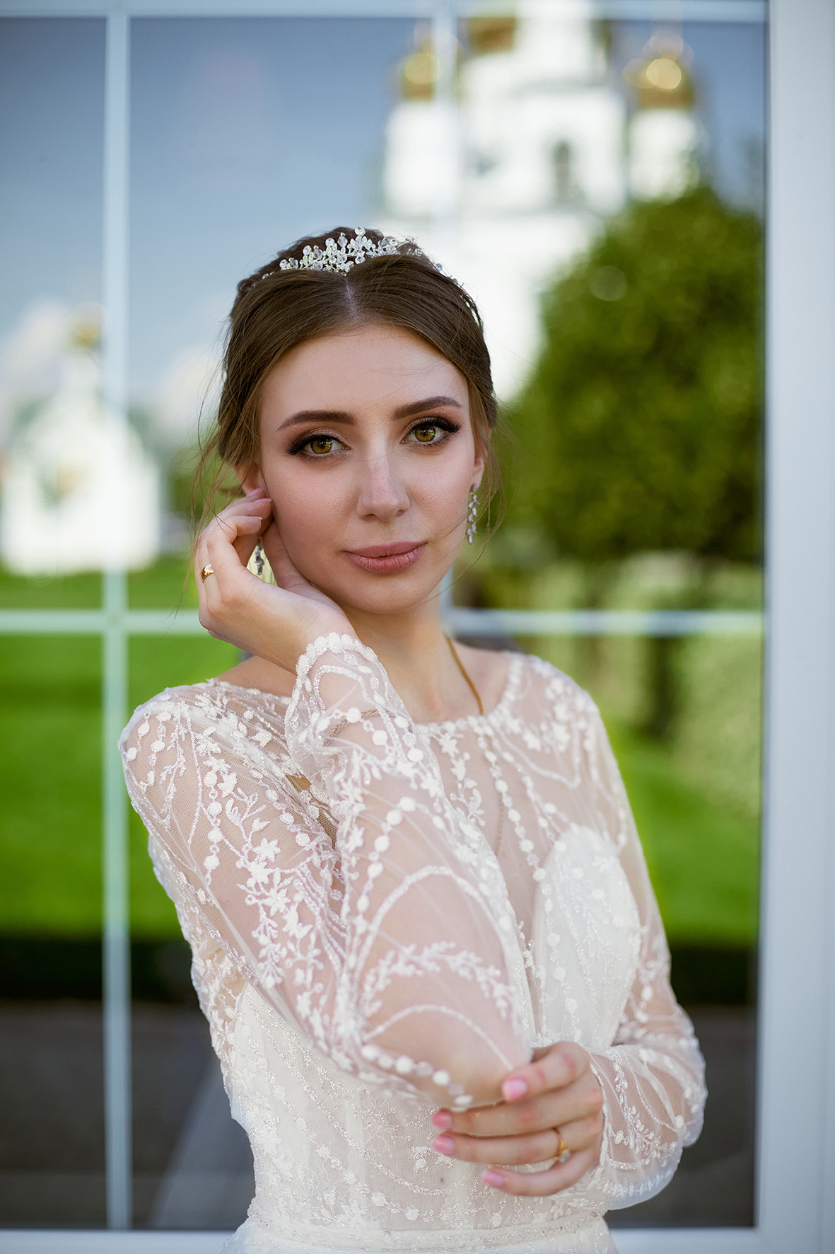 Невеста стоит напротив зеркальной витрины, в которой отражается храм. Фотограф. Кубань. Краснодарский край. Тимашевск.