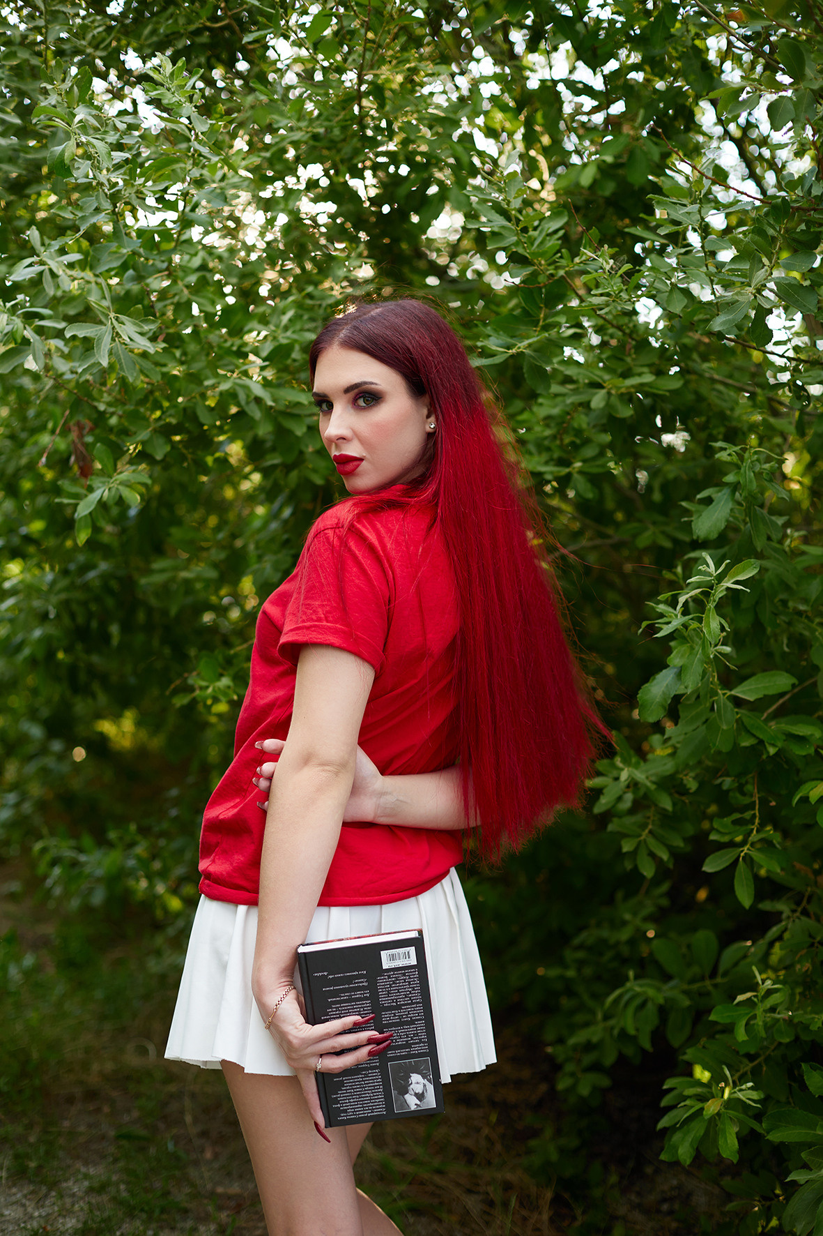 Девушка с красными волосами читает книгу Стивена Кинга в саду среди деревьев. Фотограф. Тимашевск. Кубань. Краснодарский край.