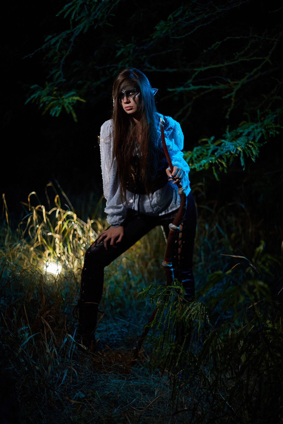 Боевой эльф с черным макияжем с луком и стрелой в руках стоит в ночном лесу. Фотограф. Фотоискусство. Краснодарский край. Кубань. Тимашевск.