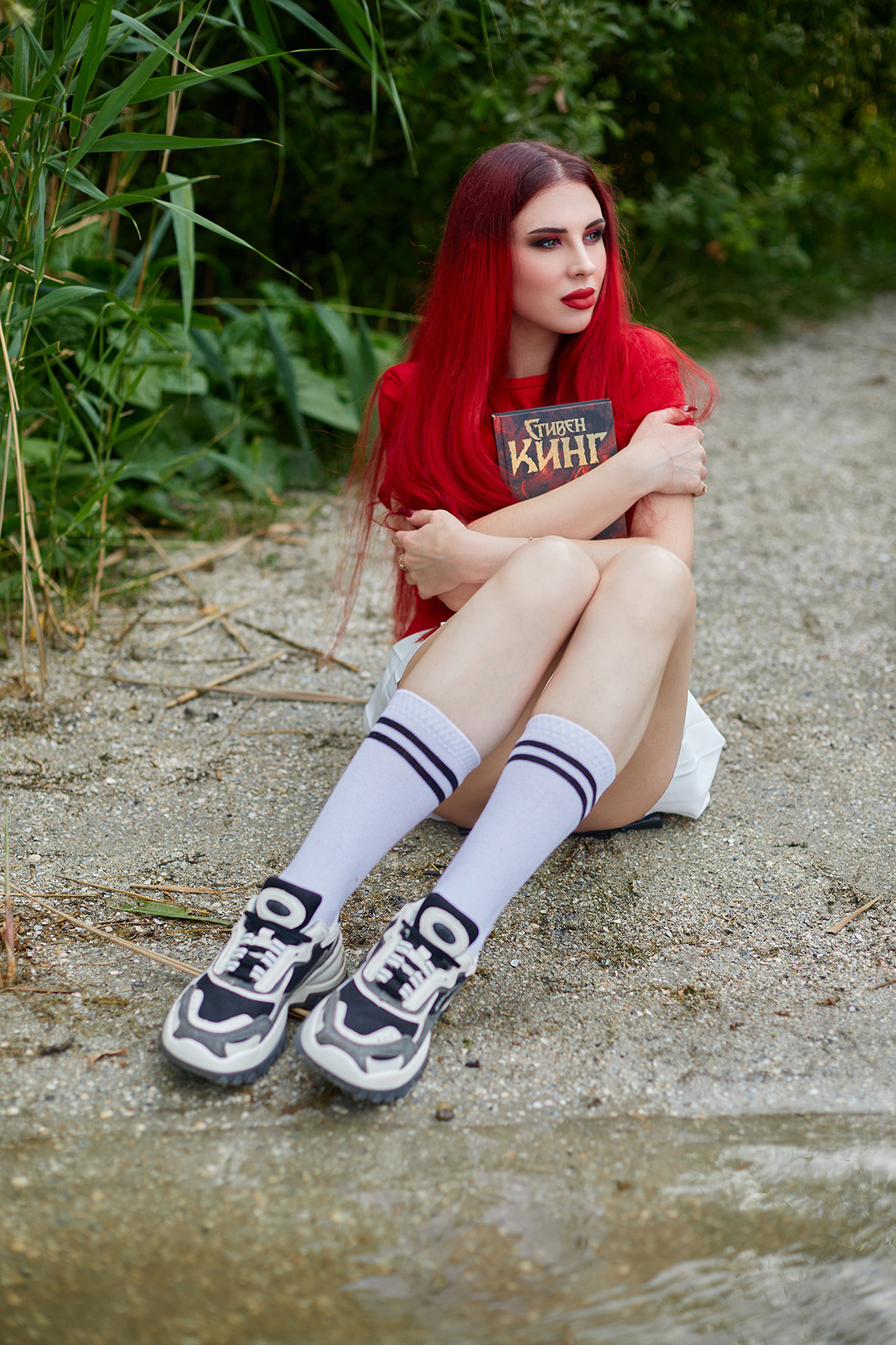 Девушка с красными волосами читает книгу Стивена Кинга на берегу реки. Фотограф. Тимашевск. Кубань. Краснодарский край.