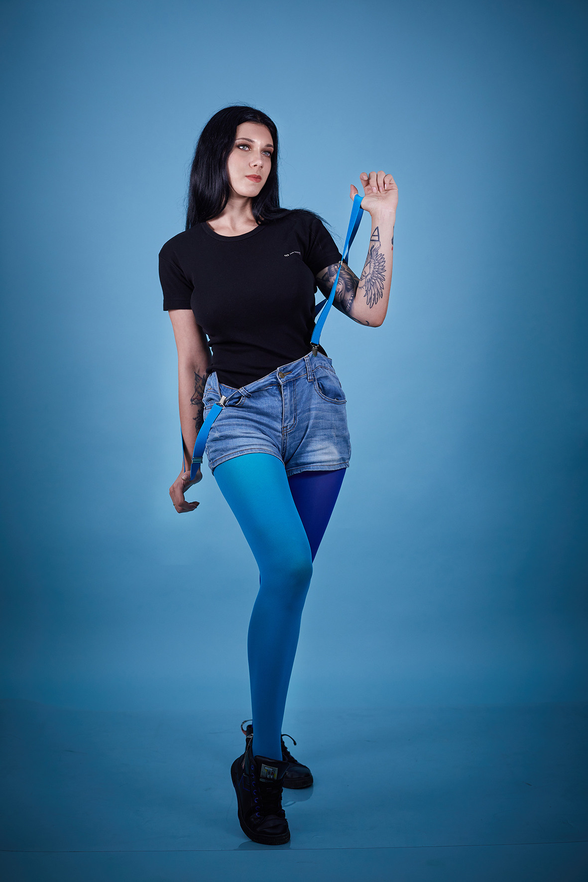 Студийные портрет девушки на голубом фоне. Девушка с татуировками в шортах на подтяжках. Фотограф. Тимашевск. Кубань. Краснодарский край.