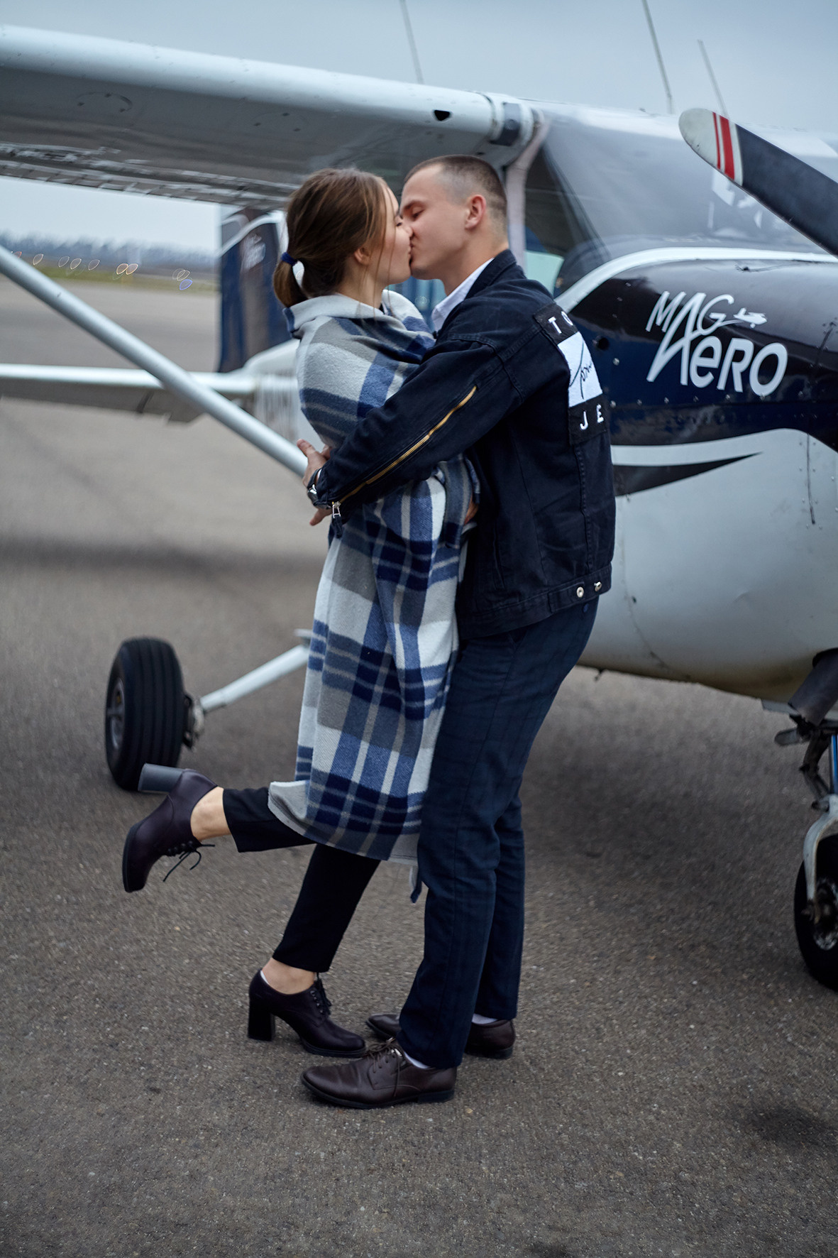 Лавстори на частном самолете. Парень дарит девушке полет на самолете. Парень и девушка в клетчатом пледе целуются возле самолета. Фотограф. Тимашевск. Кубань. Краснодарский край.