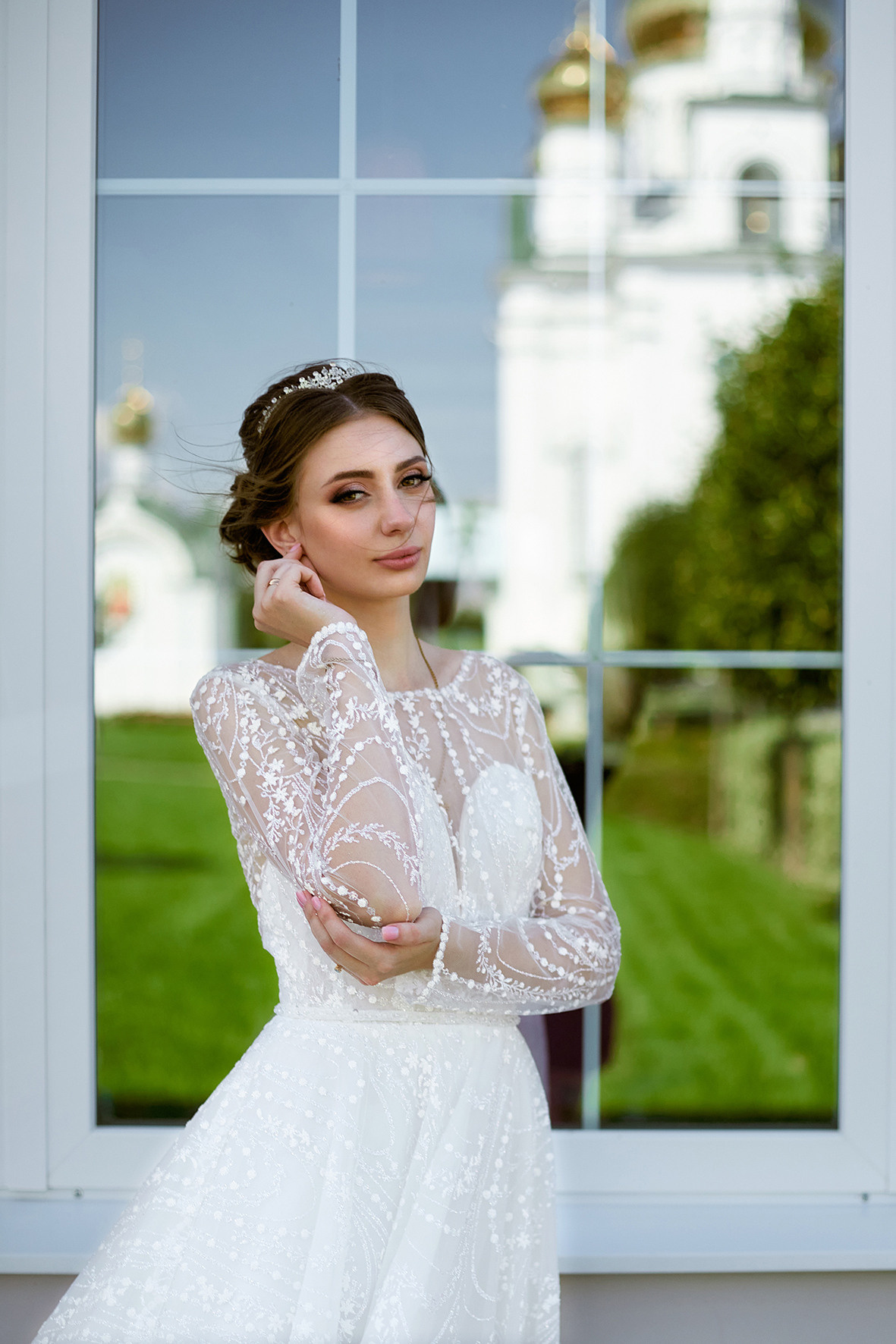 Невеста стоит напротив зеркальной витрины, в которой отражается храм. Фотограф. Кубань. Краснодарский край. Тимашевск.