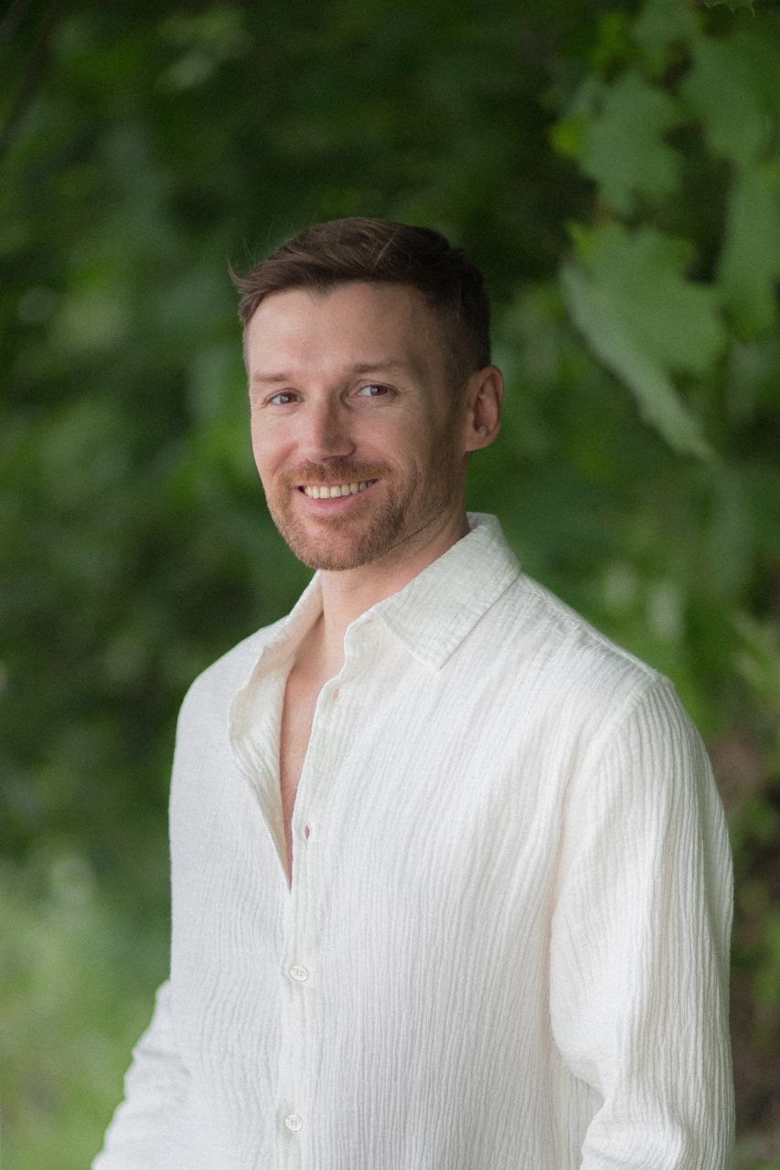 Мужчина в белой рубашке на фоне зелени