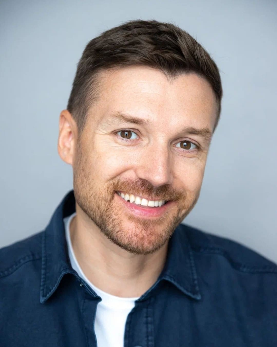 Портрет кареглазого мужчины с короткой щетиной в синей рубашке