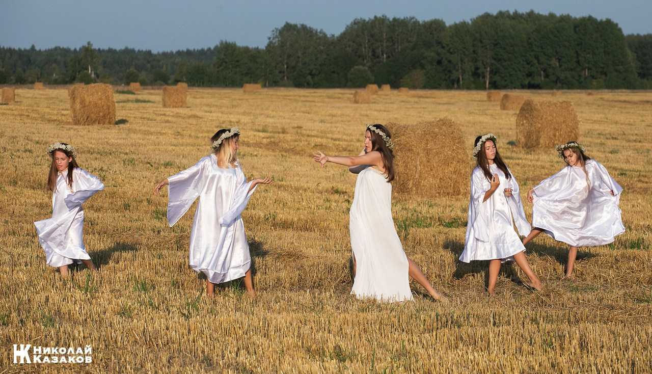 Стройные девочки подростки танцуют в пшеничном поле во время фотосессии на закате.