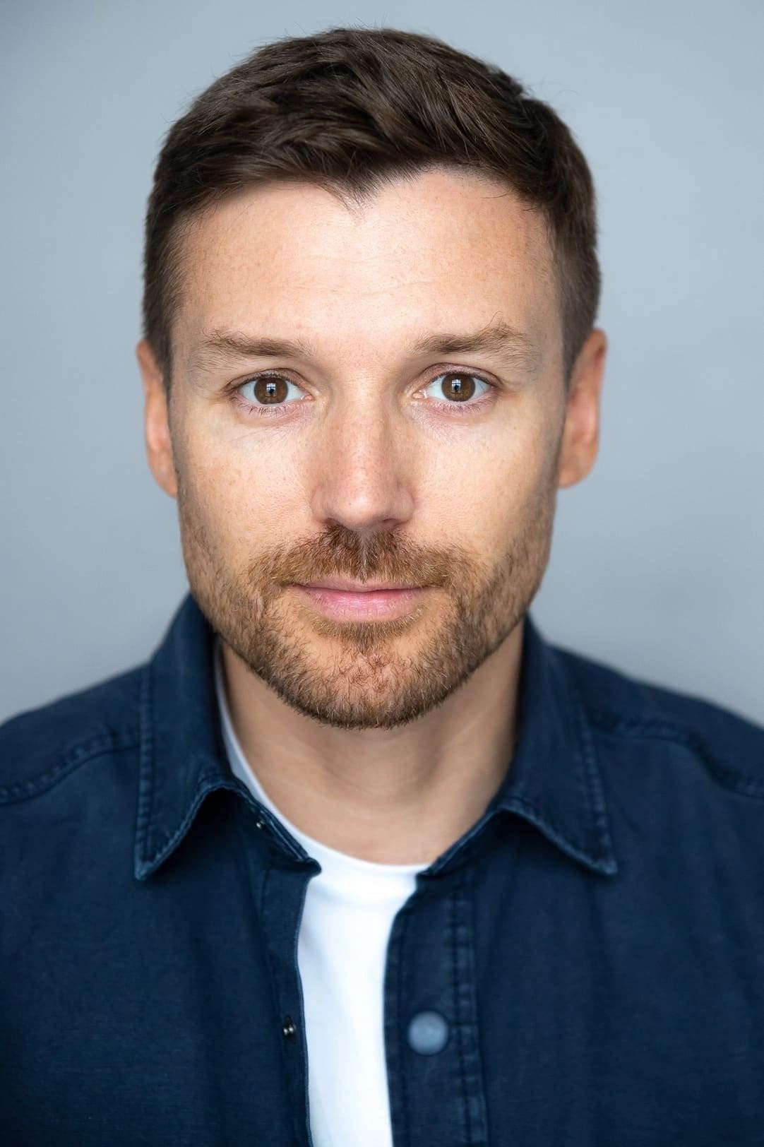 Портрет кареглазого мужчины с короткой щетиной в синей рубашке