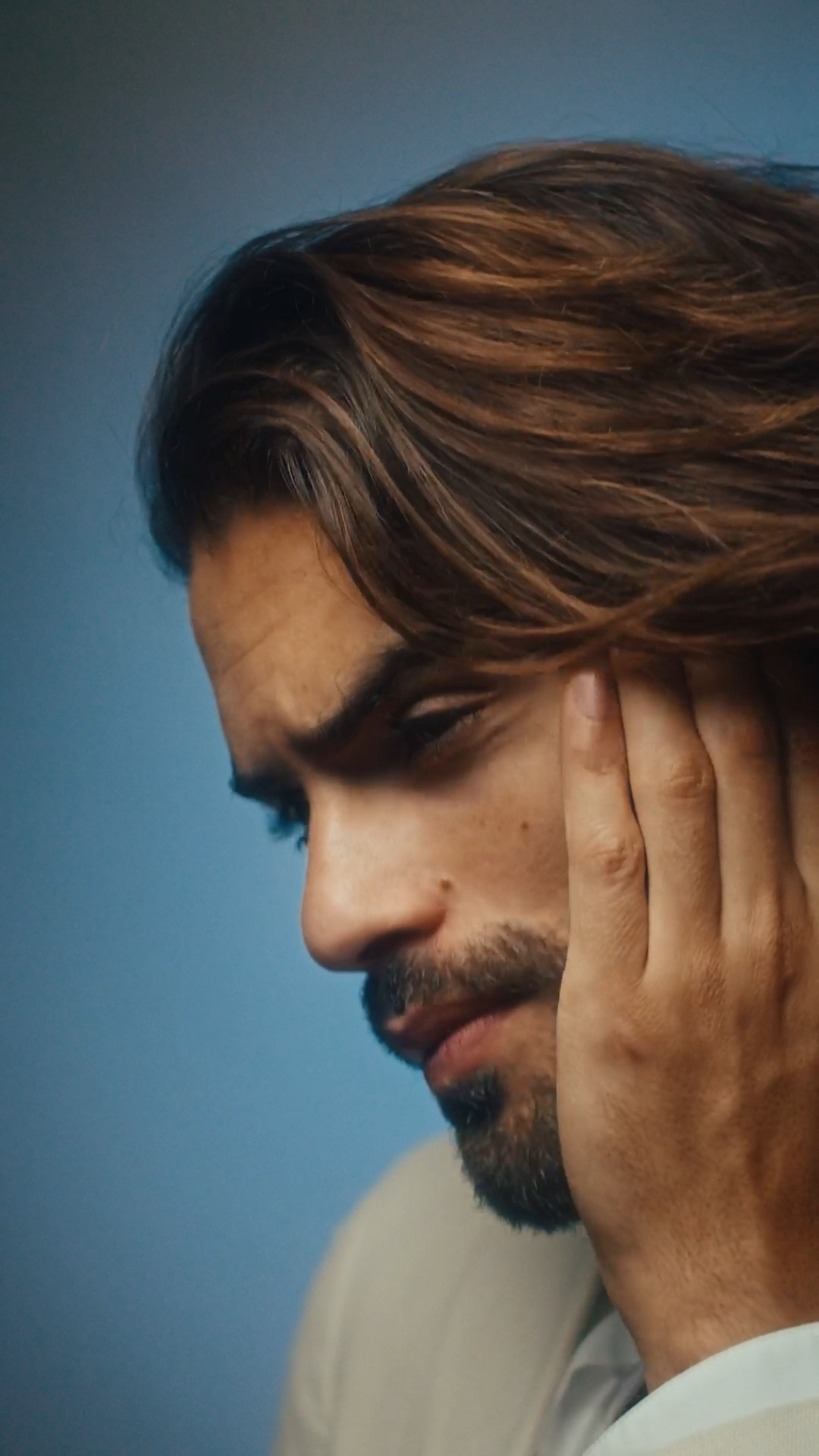 Close-up of a man adjusting his tie in a beige suit, emphasizing polished style.