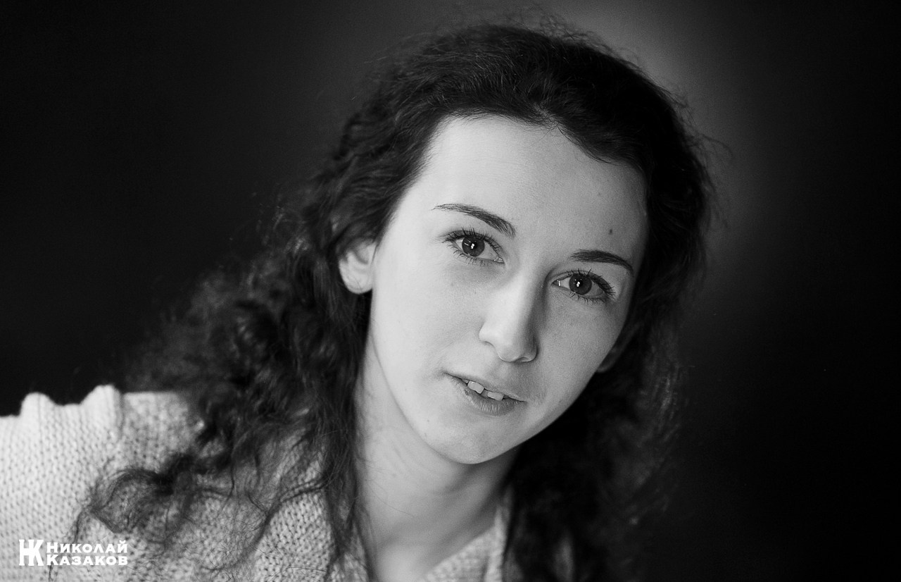 Портрет красивой молодой женщины на темном фоне во время фотосъемки для актерского портфолио.