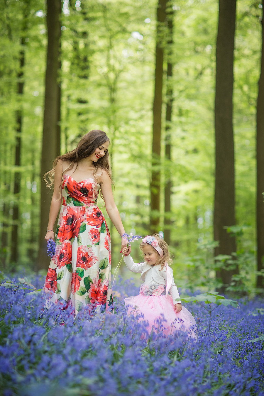 мама и дочка в красивых платьях идут по фиолетовому ковру из цветов - колокольчиков