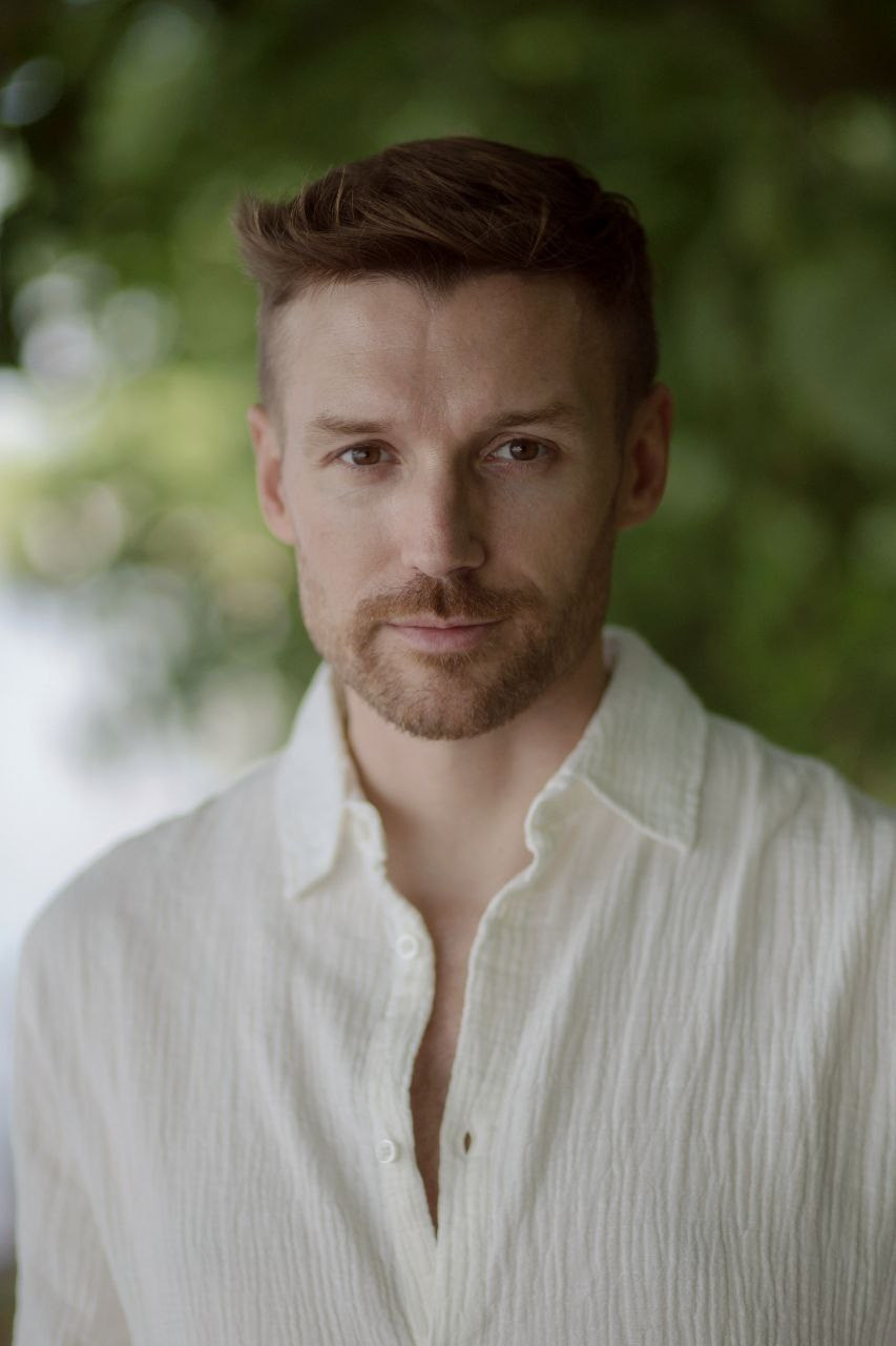 Мужчина в белой рубашке на фоне зелени