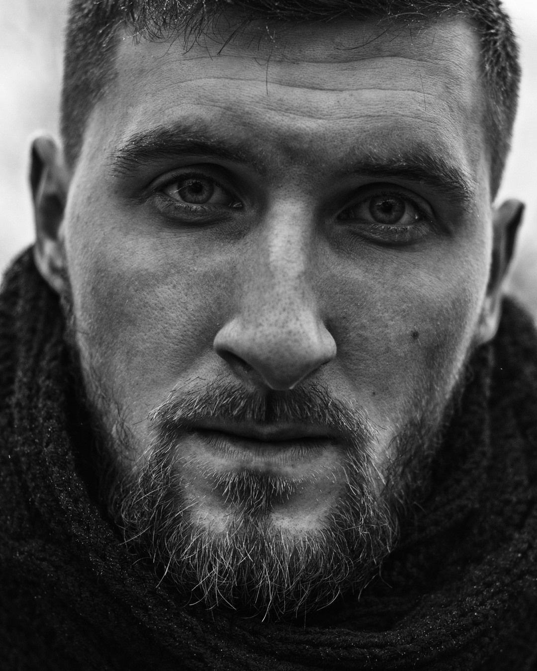 Фотограф Роман Романов — крупный мужской черно-белый портрет парня с бородой и шарфом.