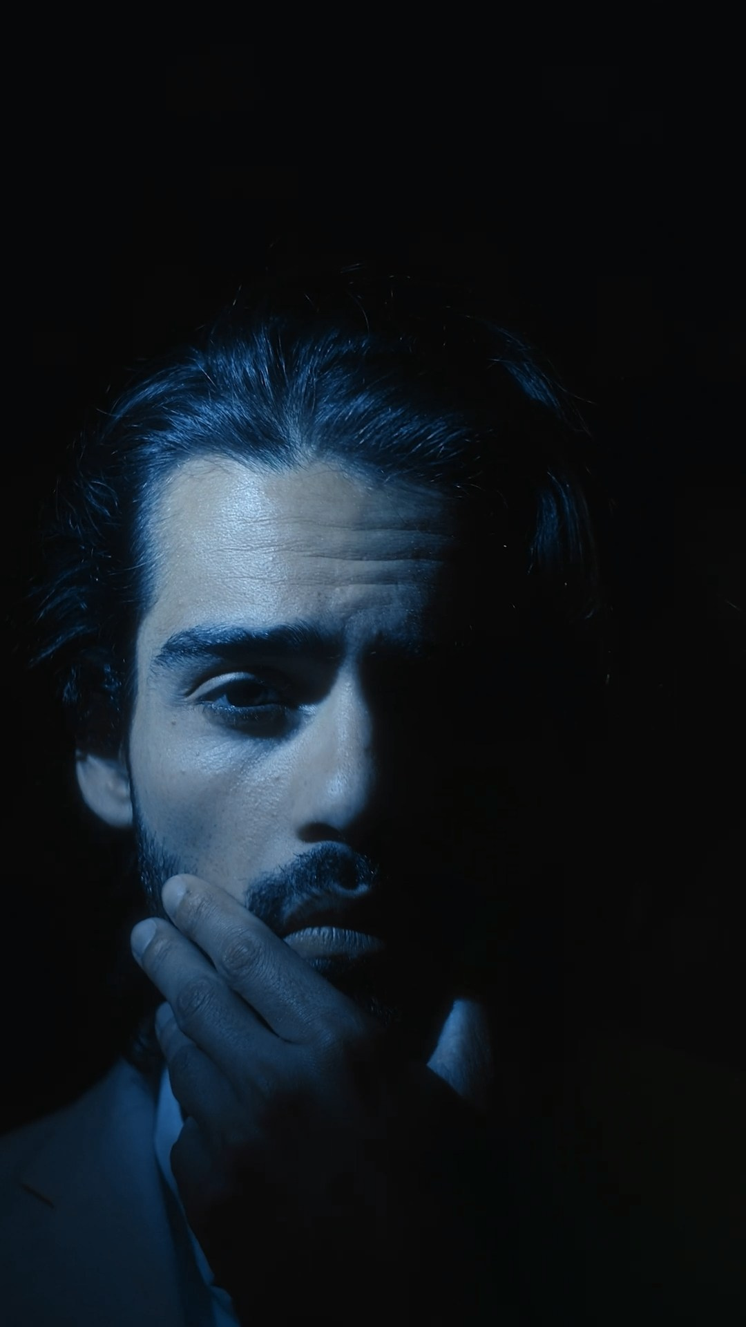 Portrait of a male model in dramatic lighting, creating a moody and sophisticated fashion aesthetic.