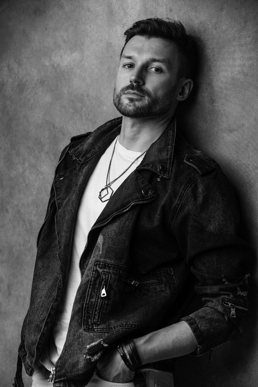 Мужчина с короткой щетиной в джинсовой куртке и белой футболке