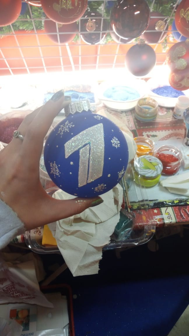 стеклянный елочный шар в руках у художника для первого канала с логотипом