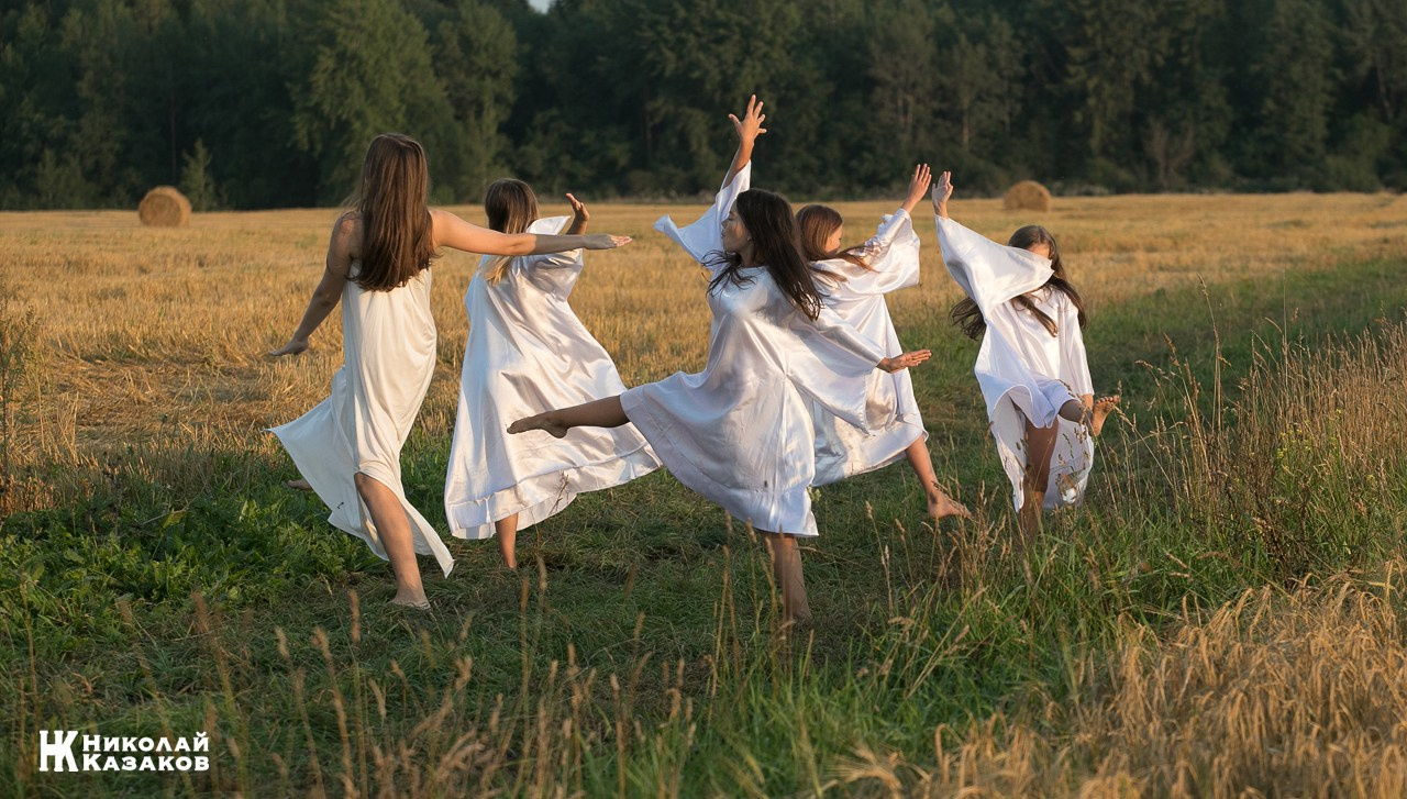 Стройные девочки подростки танцуют в пшеничном поле во время фотосессии на закате.