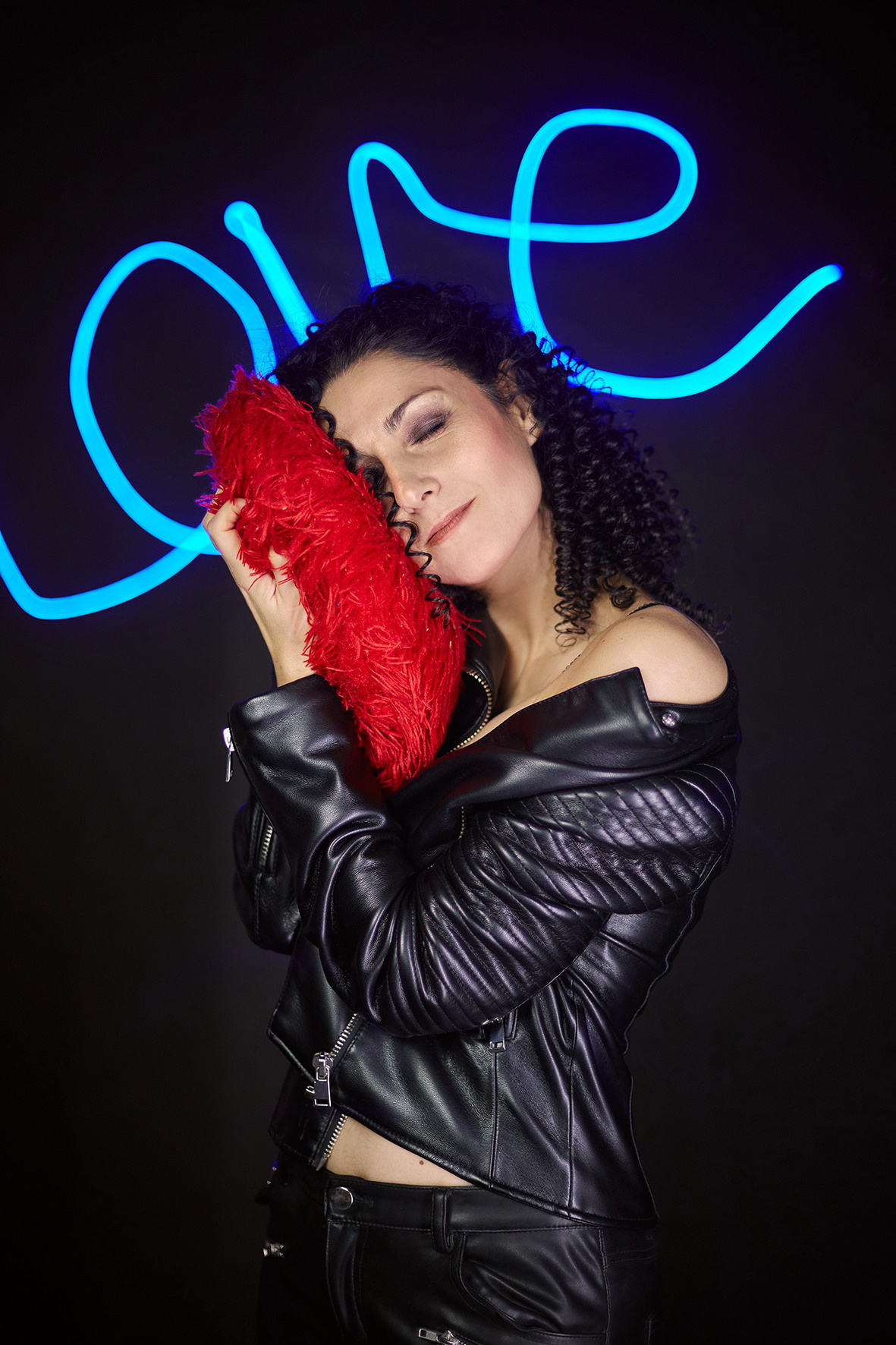 Девушка с мягким красным сердцем стоит на фоне светодиодной надписи love. Фотограф. Тимашевск. Кубань. Краснодарский край.