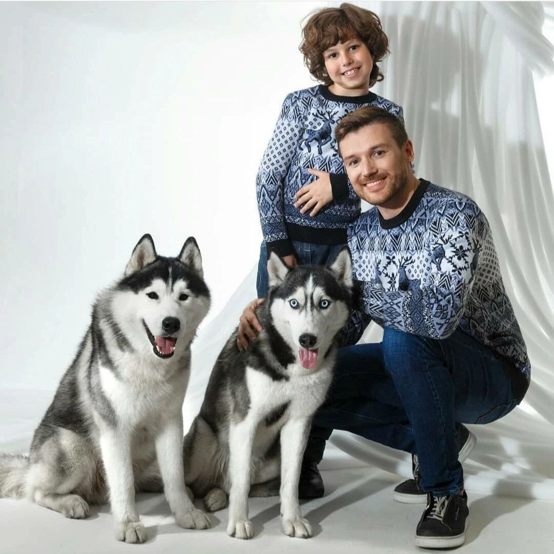 Мужчина и мальчик в свитерах с двумя собаками породы хаски