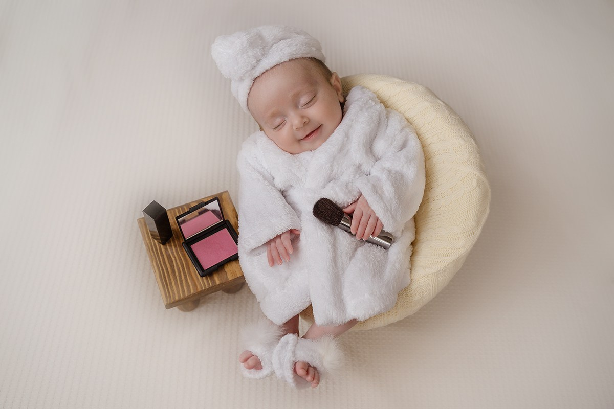 новорожденная в кресле с чалмой на голове и косметикой