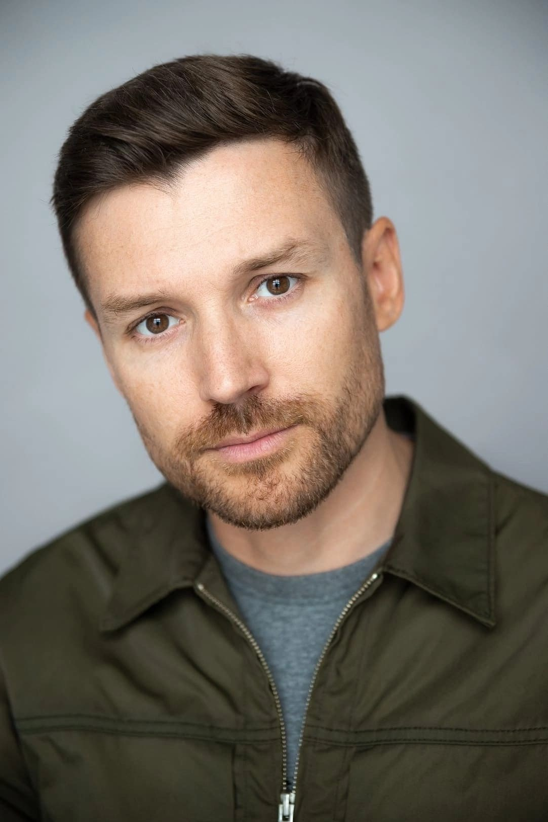 Портрет мужчины с короткой щетиной в зеленой куртке