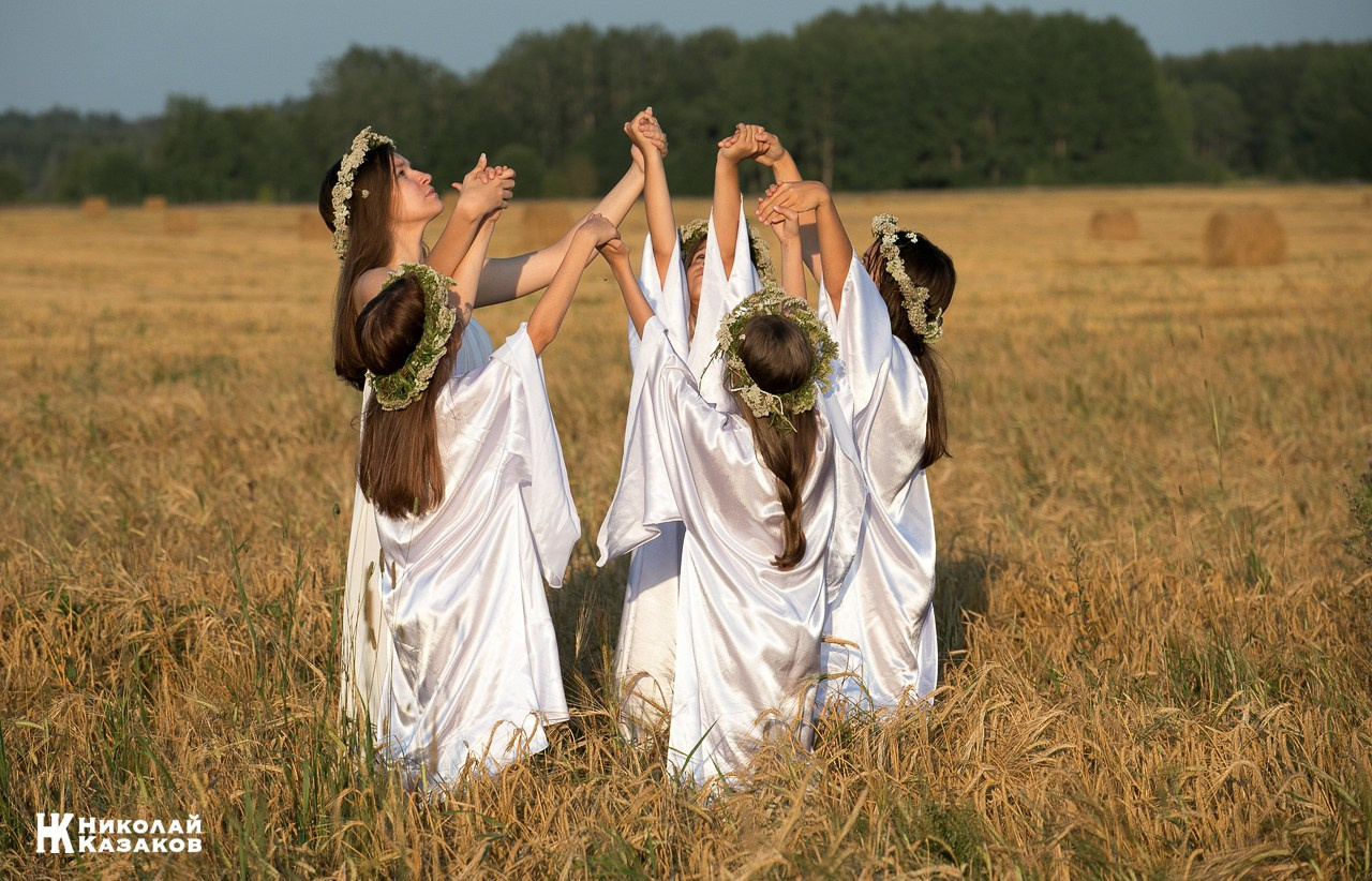 Стройные девочки подростки танцуют в пшеничном поле во время фотосессии на закате.