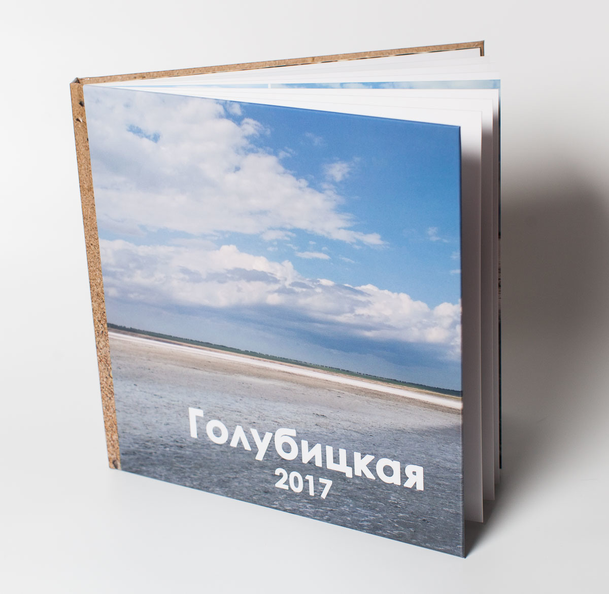 Квадратный фотоальбом на белом фоне с фотографией неба и моря на обложке.